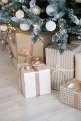 Designer Christmas tree decoration with light decorations. The concept of celebrating New Year and Christmas. Gifts in craft packaging under the Christmas tree.