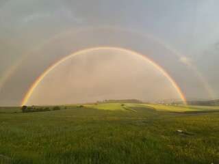 a whole rainbow behind it forests and meadows