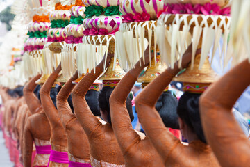 Procession of beautiful Balinese women in traditional costumes - sarong, carry offering on heads for Hindu ceremony. Arts festival, culture of Bali island and Indonesia people, Asian travel background