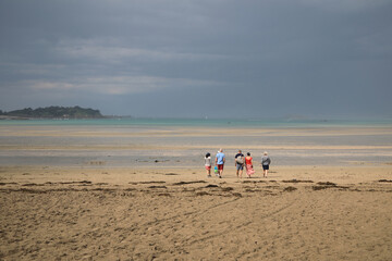 Family walking toward the sea at the beach (Sait Jacut de la Mer village in french Brittany)