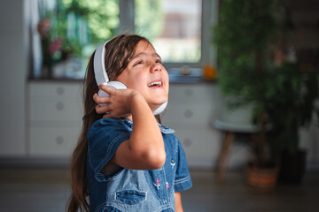 Little girl enjoying music with headphones at home