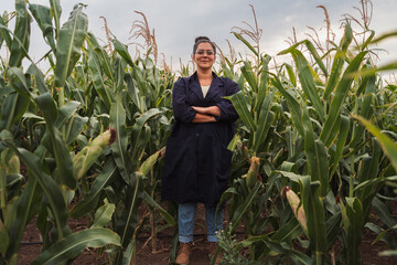 Confident female agronomist standing in a cornfield with arms crossed