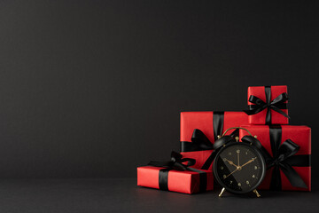 Side view composition of red gift boxes with black ribbons and a clock, celebrating Black Friday...
