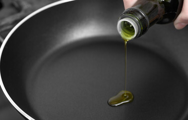 Close-up of cooking oil being poured from a bottle into a pan