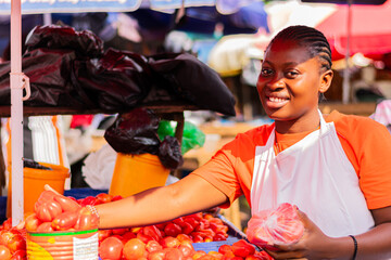 Young, excited African market woman holding tomatoes to sell