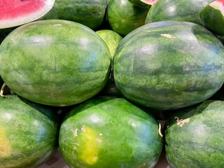 Fresh watermelons stacked at a market, showcasing vibrant green rinds and juicy red flesh, perfect for summer refreshment and healthy eating.