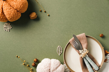 Autumn table flatlay with plush pumpkins, rustic cutlery, walnuts, acorns, and wooden leaf decor....