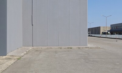 Gray prefab concrete building with a street and other warehouses on the right in an industrial...