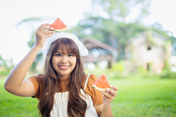 Young woman enjoys picnic outdoors holding watermelon slices with happy smile, capturing leisure...