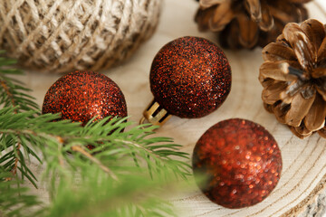 Christmas decorations with red glitter baubles and pine cones on wooden background