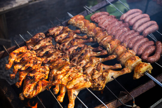 Espetos de uma churrasqueira com frango assado e lingui&ccedil;a toscana 