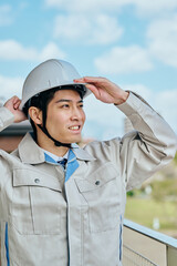 ヘルメットをかぶる作業服姿の男性