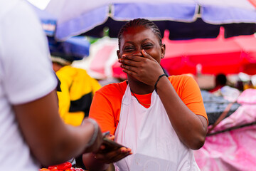 African market woman selling tomatoes and collecting cashless payment from customer