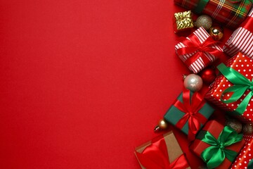 Elegant arrangement of wrapped Christmas gifts and golden decorations on red surface