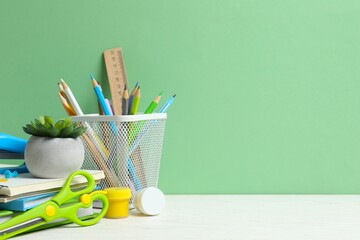 Colorful and modern workspace with pencil holder, notebooks and green wall.