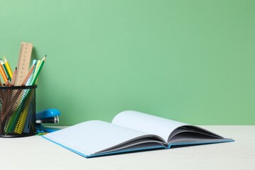 Close-up of open notebook, colorful stationery on green chalkboard background