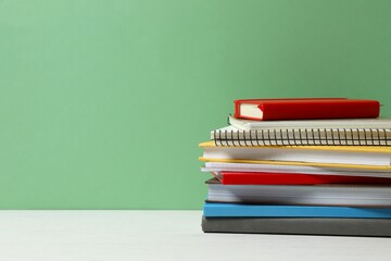Stack of different books and notebooks on white table
