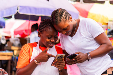 Young, excited African market woman shown a successful transaction on her smartphone