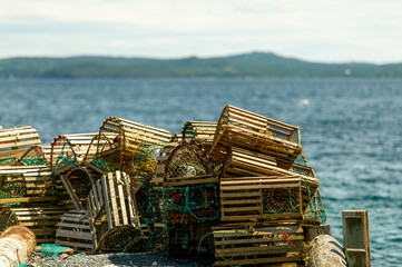 Close-up view of a cluster of traditional wooden lobster traps stacked on a weathered dock in...