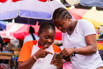 Young, excited African market woman shown a successful transaction on her smartphone