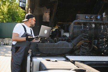 Truck service and maintenance. Vehicle mechanic with diagnostic tool laptop working