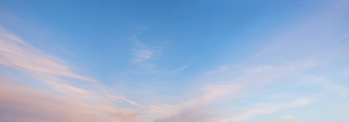 wide sky panorama with soft pink cirrostrati clouds in the lower half and blue sky above