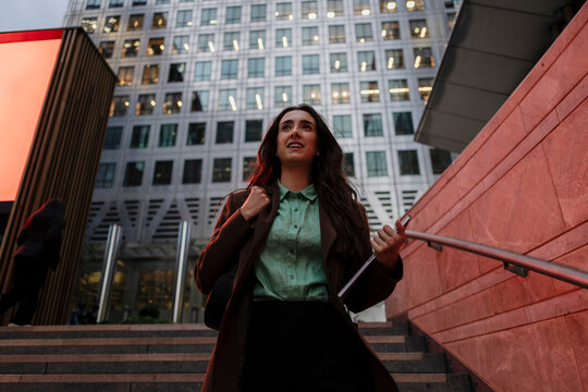 Businesswoman with tablet walking outdoors by office in Canary Wharf