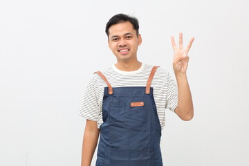 Asian young man wearing apron over white background showing three fingers with exited and happy face expression