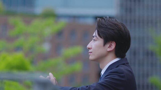ビルを背景に遠くを見つめるスーツを着た日本人ビジネスマンの男性	