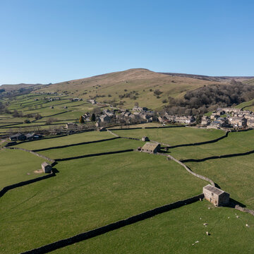 elevated view of patchwork fields and traditional stone barns at gunnerside village in swaledale north yorkshire england