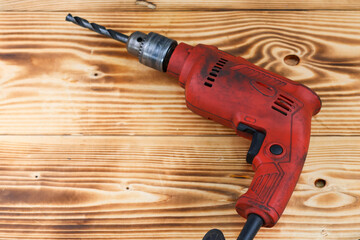 Red Electric hand drill set on wooden table, electric carpenter tool.
