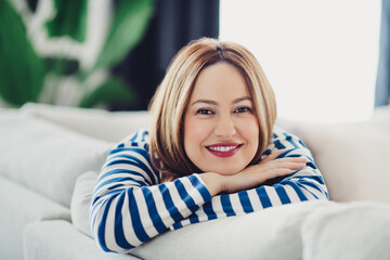 Charming woman enjoying a relaxed weekend moment indoors in casual striped sweater