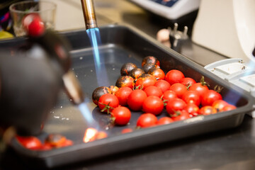 Cherry tomatoes are grilled with a gas burner