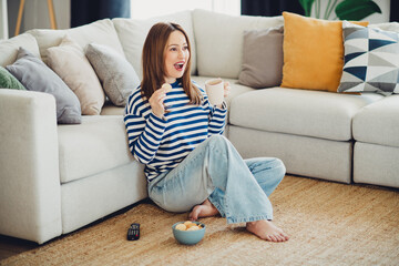 Smiling woman relaxing at home with a cup of coffee while sitting on the carpet in the living room