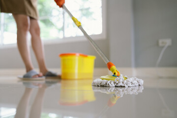 A woman mops the floor with a bucket nearby, representing housekeeping, hygiene, cleanliness, domestic chores, home care, sanitation, tidiness, professional cleaning service, household maintenance, an