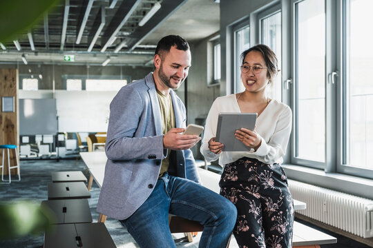 Business colleagues with wireless technologies sitting at desk in office