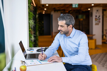 Businessman writing ideas on paper at co working space