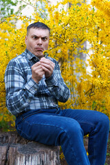 portrait of a man on the background of yellow forsythia flowers, spring nature and blossoms