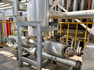 A detailed shot of insulated industrial pipes, valves, and a metallic support structure in a factory or plant setting.