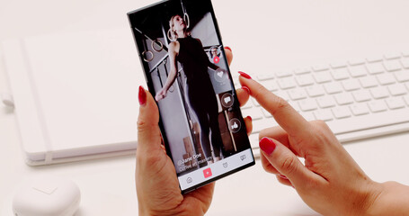Young Woman Scrolling Through Short Videos On Mobile Phone