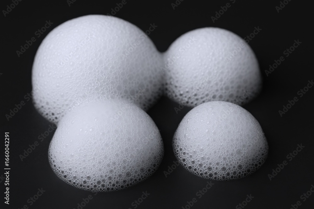 Poster close-up of four luminous foam bubbles on a sleek black surface, creating an abstract pattern