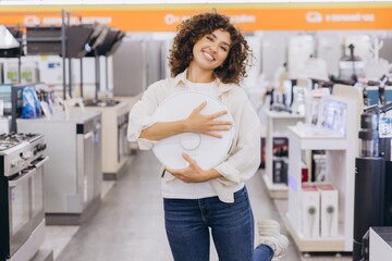 Woman Holding Robotic Vacuum Cleaner in Appliance Store