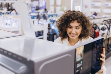 Woman Choosing Microwave Oven in Electronics Store