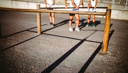 Four athletes engage in a stretching exercise using a wooden outdoor obstacle course.