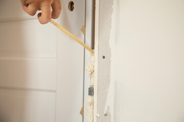 Worker spray construction foam between new door.