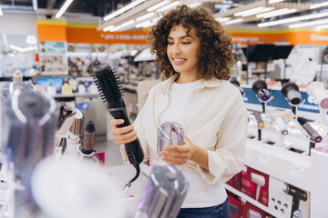 Woman choosing hair dryer in electronics store