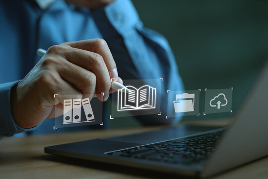Businessman using digital pen on laptop with document, folder, book, and cloud upload icons. Concept of digital document management, knowledge base, e-library, cloud storage and online learning.