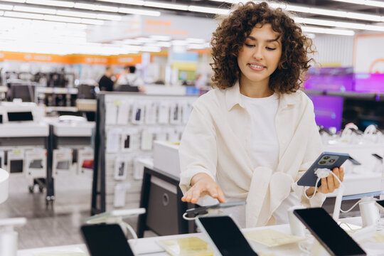 Woman comparing smartphones in electronics store