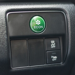 Green ECON button in car dashboard, economy switch for power saving, economical energy driving technology in EV electric vehicle and hybrid engine automobile system