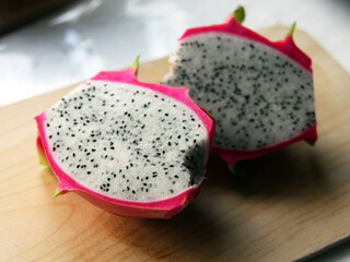 Dragon fruit, pitaya, pitahaya on a wooden board on a white background. Exotic fruit cut in half. White pulp with seeds. Cactus fruit